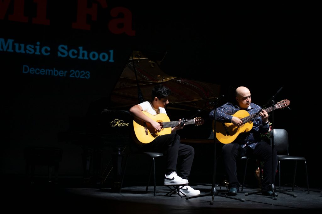 two people playing guitar at a music school