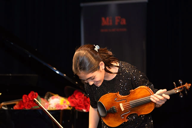 A girl holding a guitar after performing at the Mifa Music School in North Vancouver.