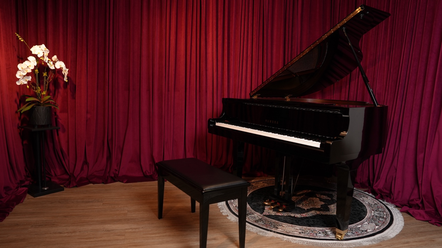 Grand piano in MiFa’s piano room with burgundy curtains