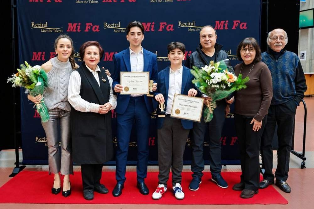 MiFa students holding certificates and trophies with family